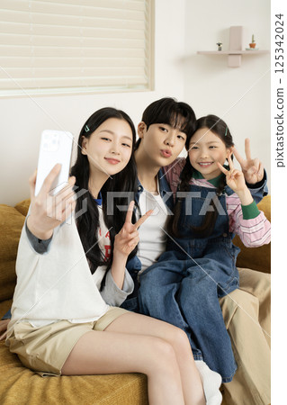Daughter building domino blocks with her mother and father sitting on the sofa 125342024