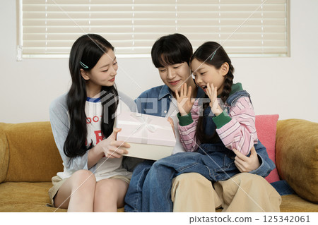 A family sitting side by side on a bed 125342061