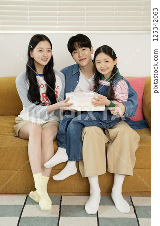 A family sitting side by side on a bed 125342063