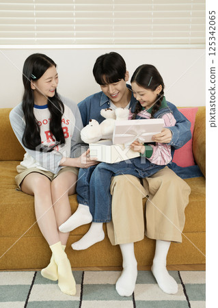 A family sitting side by side on a bed 125342065
