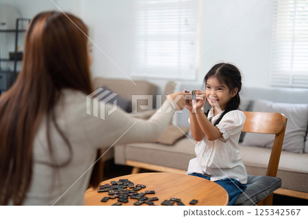 Educational Play and Interaction. A girl eagerly participates in a game, learning valuable skills with her mother. Educational Play and Interaction. A girl eagerly participates in a game, learning valuable skills with her mother. 125342567