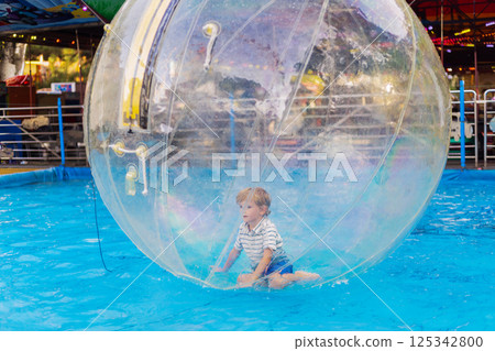 Boy inside inflatable water ball on pool 125342800