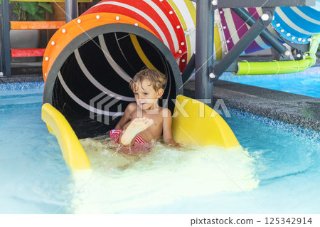 Child on colorful water slide exit 125342914