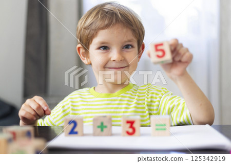 Smiling boy learning math with wooden blocks 125342919