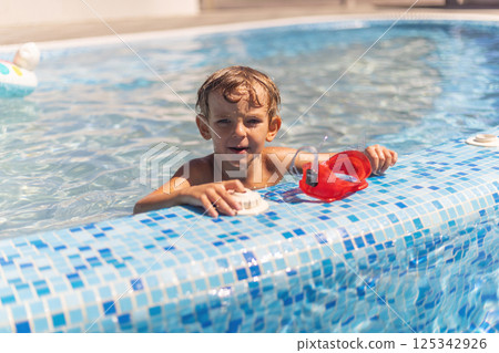 Boy leaning on edge of swimming pool Boy leaning on edge of swimming pool 125342926