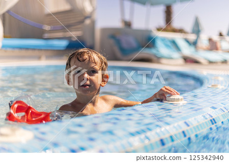 Boy relaxing in swimming pool outdoors Boy relaxing in swimming pool outdoors 125342940