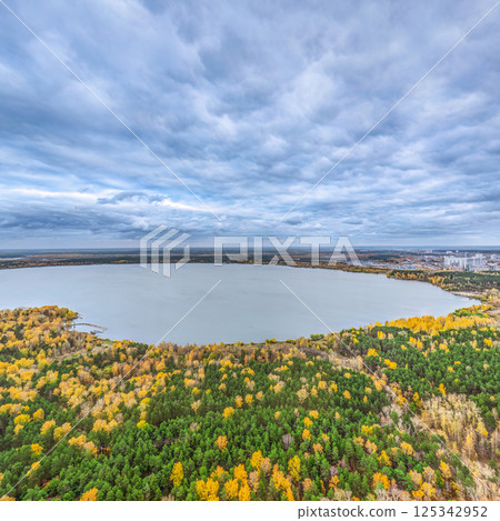 Autumn forest on lake shore at sunset and city on horizon, auerial view Autumn forest on lake shore at sunset and city on horizon, auerial view 125342952
