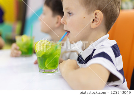 Boy drinking green mocktail with lime slices 125343049