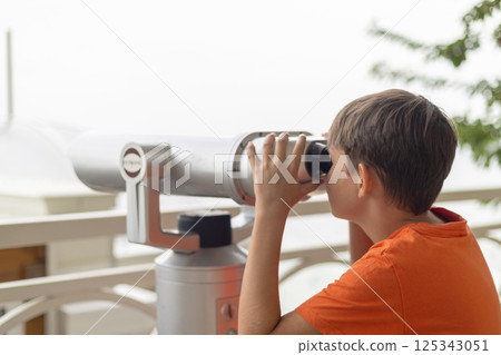 Boy looking through outdoor telescope 125343051