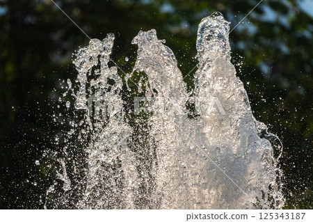 Splashes of water on dark background. Water sprays in sunny day close-up. 125343187