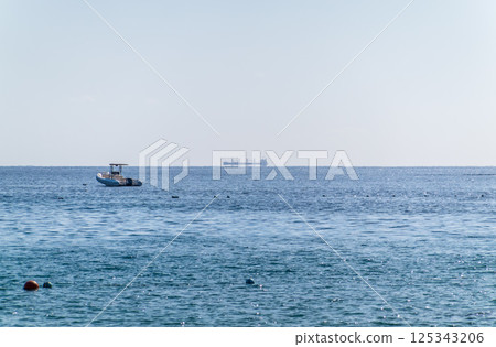 Calm blue sea with the silhouette of a large ship on the horizon Calm blue sea with the silhouette of a large ship on the horizon 125343206