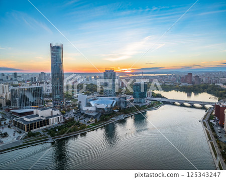 Yekaterinburg city and pond aerial panoramic view at summer or early autumn sunset. Night city in the early autumn or summer. Yekaterinburg city and pond aerial panoramic view at summer or early autumn sunset. Night city in the early autumn or summer. 125343247
