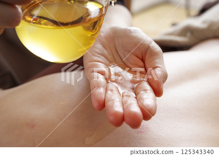 Aesthetician dripping oil onto hands 125343340