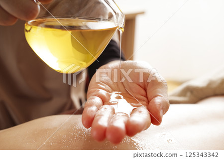 Aesthetician dripping oil onto hands 125343342