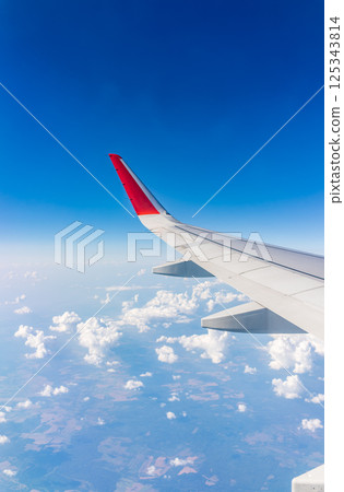 View from the airplane window at a beautiful cloudy sky and the airplane wing View from the airplane window at a beautiful cloudy sky and the airplane wing 125343814