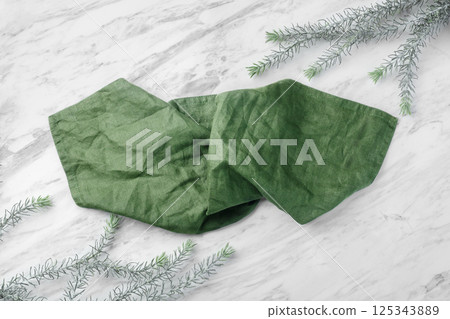 Green linen kitchen cloth on on white natural marble table with leaves 125343889
