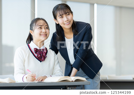 Female high school students studying at a cram school and their teacher. Photo courtesy of Denpa Gakuen, Tokyo Electronics College. 125344199