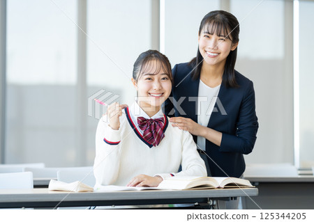 Female high school students studying at a cram school and their teacher. Photo courtesy of Denpa Gakuen, Tokyo Electronics College. 125344205