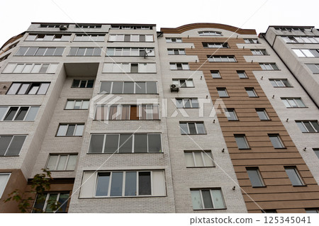 Modern residential building with large windows showcasing urban living in a metropolitan area during a cloudy day Modern residential building with large windows showcasing urban living in a metropolitan area during a cloudy day 125345041