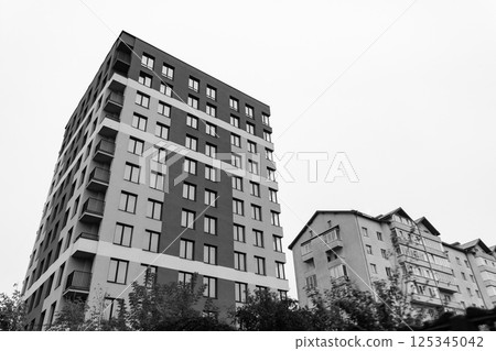 Urban architecture contrasts with modern buildings against a cloudy gray sky in a bustling city neighborhood 125345042