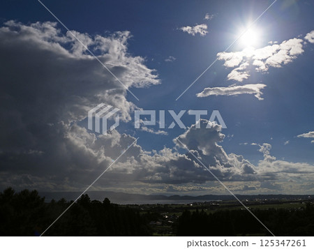 On a summer afternoon, the cumulonimbus clouds rising above Lake Inawashiro and the white shining sun are striking and beautiful against the blue sky. On a summer afternoon, the cumulonimbus clouds rising above Lake Inawashiro and the white shining sun are striking and beautiful against the blue sky. 125347261