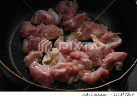 Juicy chicken thighs fried in a frying pan 125347269