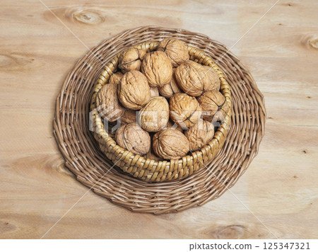 Inshell walnuts in a wicker bowl. 125347321