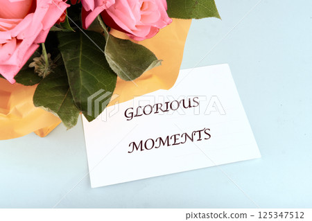 A beautiful bouquet of pink roses accompanied by a card reading Glorious Moments captures the essence of special celebrations and cherished memories shared among loved ones 125347512