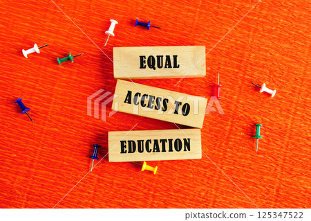 Wooden blocks spell out equal access to education, surrounded by colorful pushpins on an orange surface, symbolizing the importance of accessible education for all Wooden blocks spell out equal access to education, surrounded by colorful pushpins on an orange surface, symbolizing the importance of accessible education for all 125347522