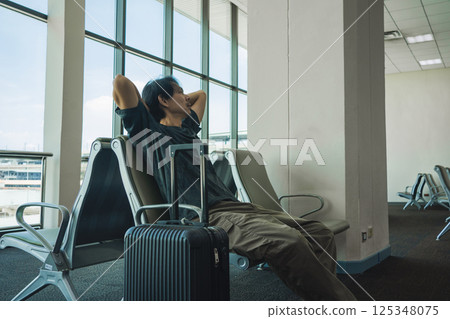 business concept with asian solo traveler wait for boarding time with luggage and seat in airport 125348075