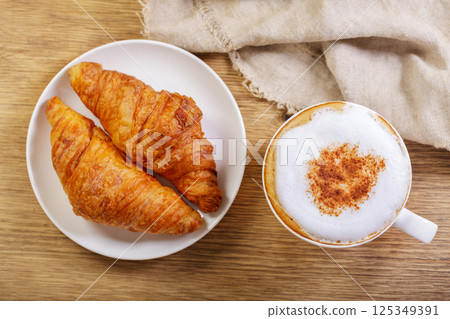 Cup of cappuccino coffee with croissants, top view Cup of cappuccino coffee with croissants, top view 125349391
