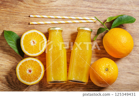 Bottles of fresh orange juice with fresh fruits on wooden background 125349431