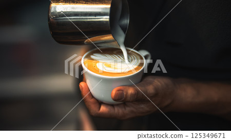 barista hand pouring milk for making latte art in cafe 125349671