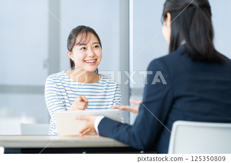 A young woman consulting with a friend. Photo courtesy of Denpa Gakuen, Tokyo Electronics College. 125350809