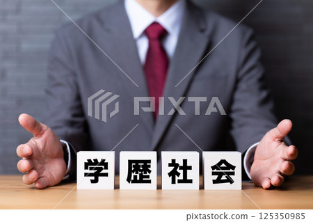 A middle-aged male businessman wearing a suit and a block of education A middle-aged male businessman wearing a suit and a block of education 125350985