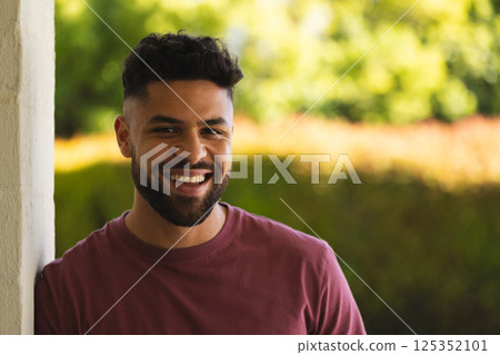 Smiling man outdoors enjoying sunny day, leaning against wall, feeling relaxed Smiling man outdoors enjoying sunny day, leaning against wall, feeling relaxed 125352101