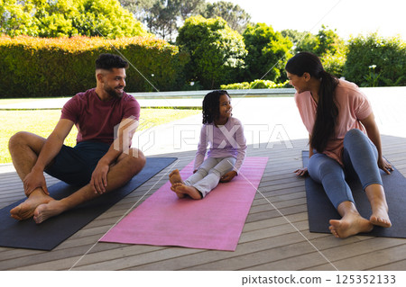 Family enjoying outdoor yoga session on mats, bonding and smiling together Family enjoying outdoor yoga session on mats, bonding and smiling together 125352133
