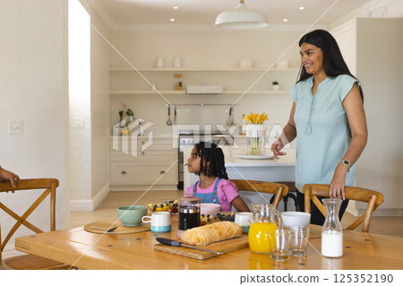 Mother and daughter enjoying breakfast together at home, sharing joyful moment 125352190