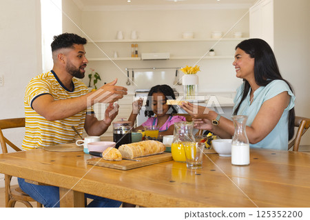 Family enjoying breakfast together at home, sharing smiles and conversation 125352200