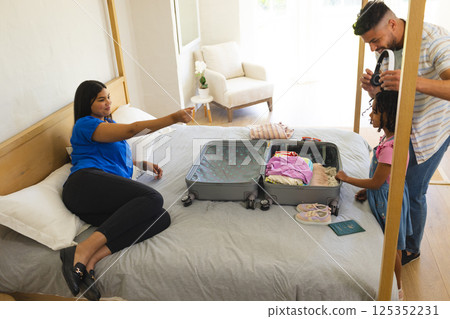 Family packing suitcase on bed, preparing for vacation with excitement and joy Family packing suitcase on bed, preparing for vacation with excitement and joy 125352231