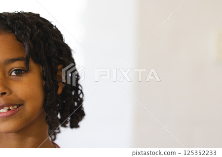 Smiling child with curly hair enjoying playful moment at home, copy space 125352233