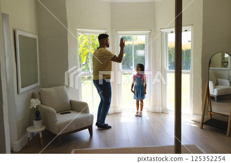 Father and daughter playing together by large windows in bright living room Father and daughter playing together by large windows in bright living room 125352254