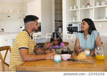 Family enjoying breakfast together at home, sharing conversation and smiles 125352258