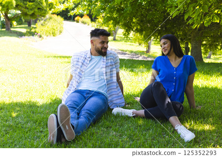 Couple relaxing on grass in park, enjoying sunny day and each other's company Couple relaxing on grass in park, enjoying sunny day and each other's company 125352293