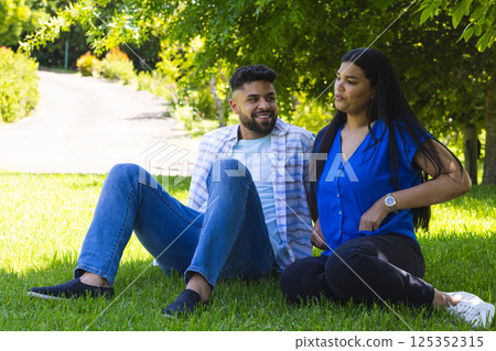 Couple relaxing on grass in park, enjoying sunny day and each other's company 125352315
