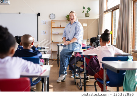 Engaging with diverse students, female teacher fostering interactive learning in classroom at school 125352986