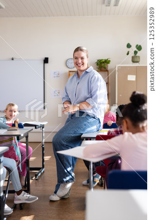 In school, female teacher smiling and engaging with diverse students in classroom setting In school, female teacher smiling and engaging with diverse students in classroom setting 125352989