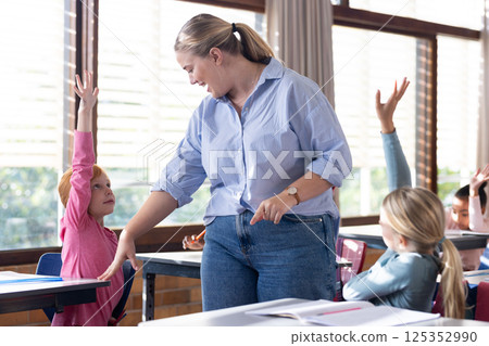 At school, raising hands, female teacher fostering active participation with diverse students At school, raising hands, female teacher fostering active participation with diverse students 125352990
