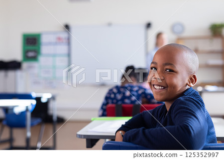 Smiling african american boy sitting at desk in classroom, enjoying school environment 125352997