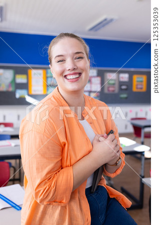 Smiling female teacher holding tablet in classroom, ready for school lesson Smiling female teacher holding tablet in classroom, ready for school lesson 125353039